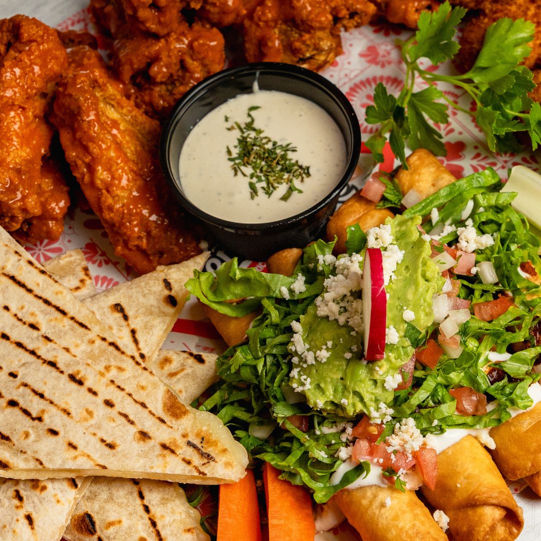 Platón para compartir con alitas búfalo, quesadillas, taquitos y guacamole