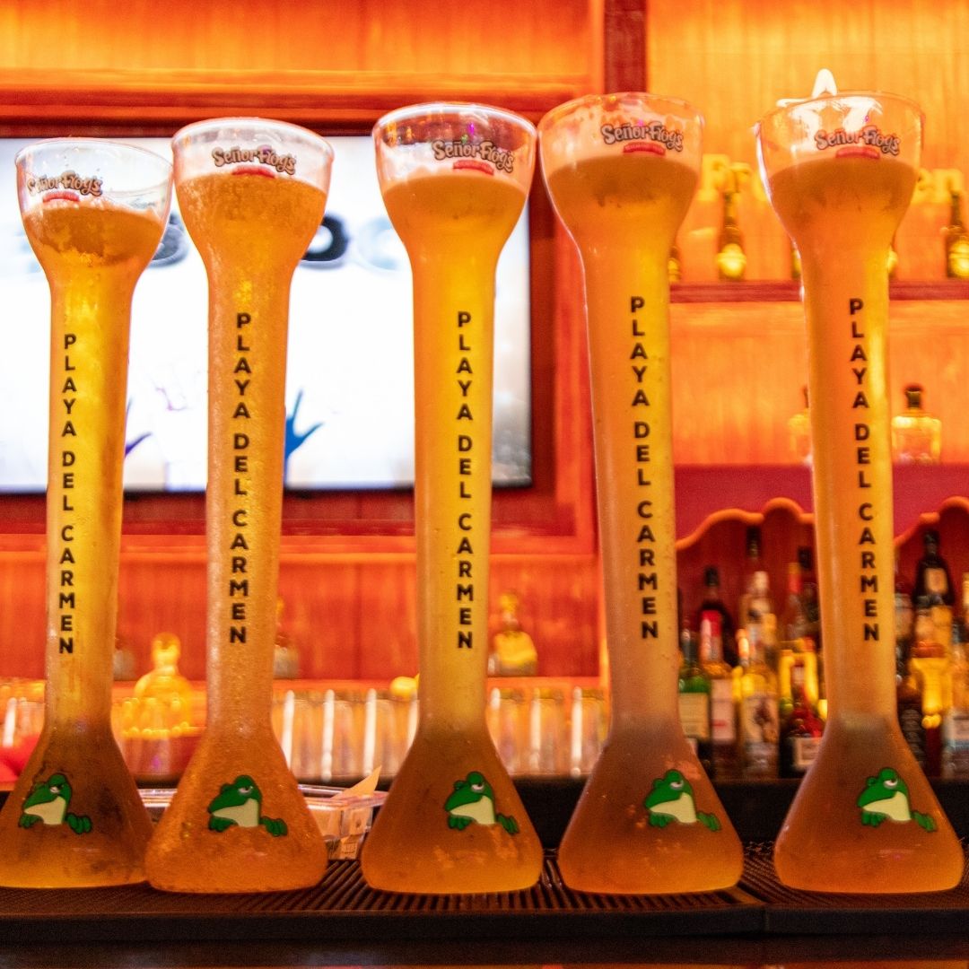 Cinco yardas de Señor Frog’s grabadas «Playa del Carmen» alineadas en la barra