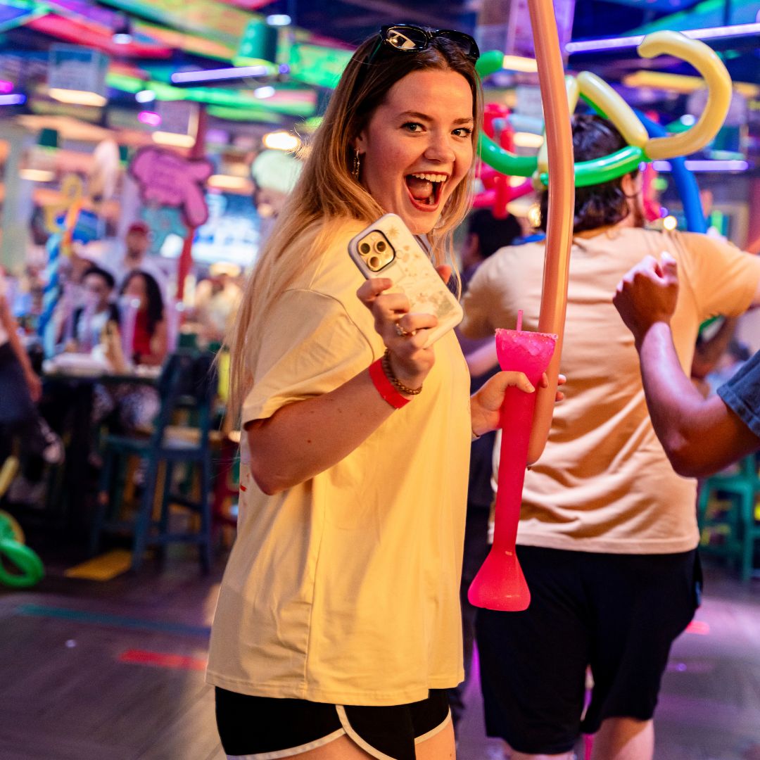 Invitada sonriendo con una yarda rosa frappe en la pista de Señor Frog’s Playa del Carmen